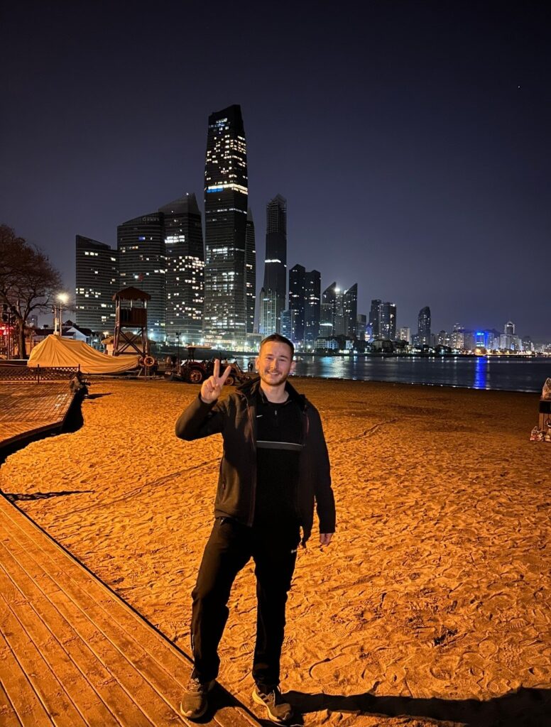 Image of David Schneider at a booth in China with skyline in the background