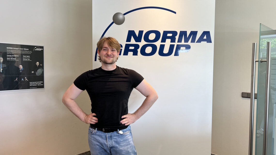 Image of working student Philipp Stiller in front of NORMA Group logo