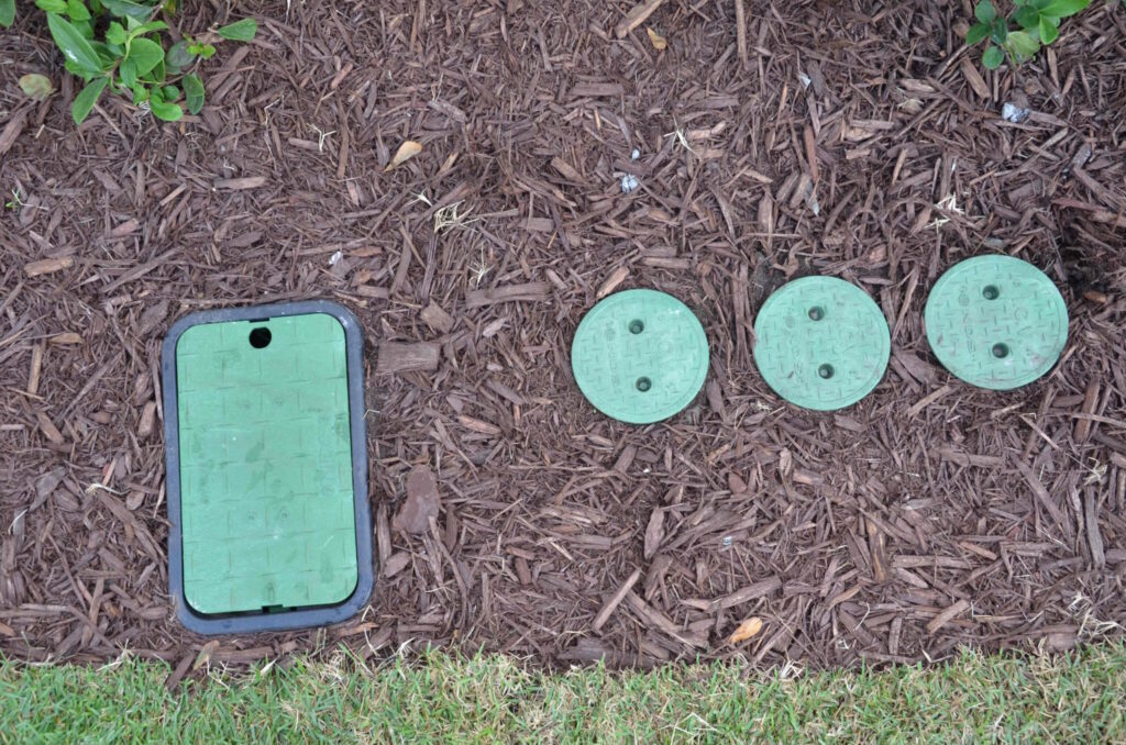 Image of rectangular and round NDS valve boxes in a garden bed